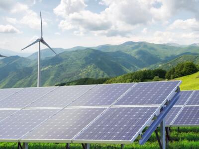 Pannelli fotovoltaici e pale eoliche su sfondo montano