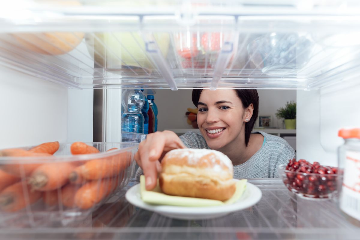 Ragazza che prende il cibo dal frigo