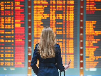 Una passeggera bloccata in aeroporto al tabellone degli orari