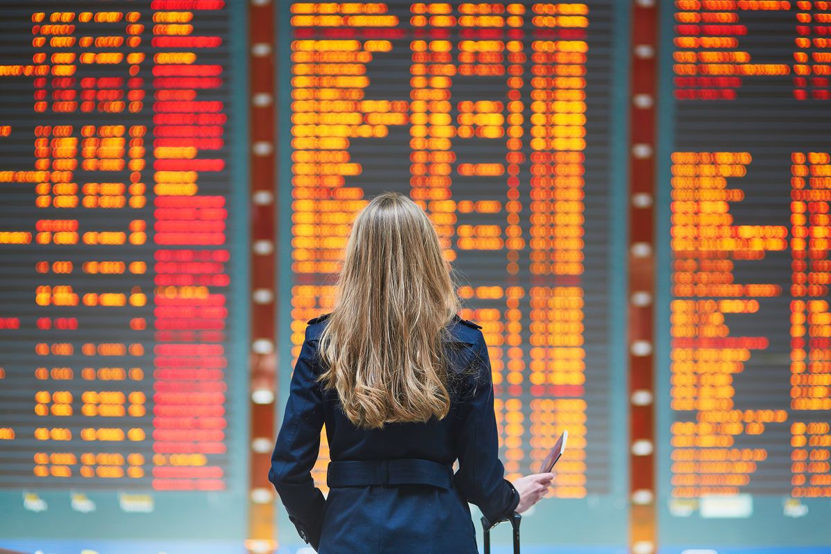 Una passeggera bloccata in aeroporto al tabellone degli orari
