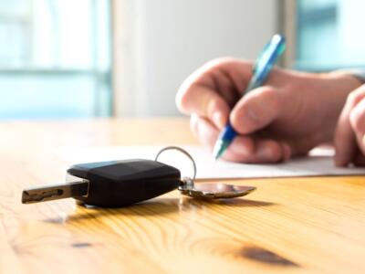 Un uomo firma un contratto di prestito finalizzato per l'acquisto dell'auto nuova