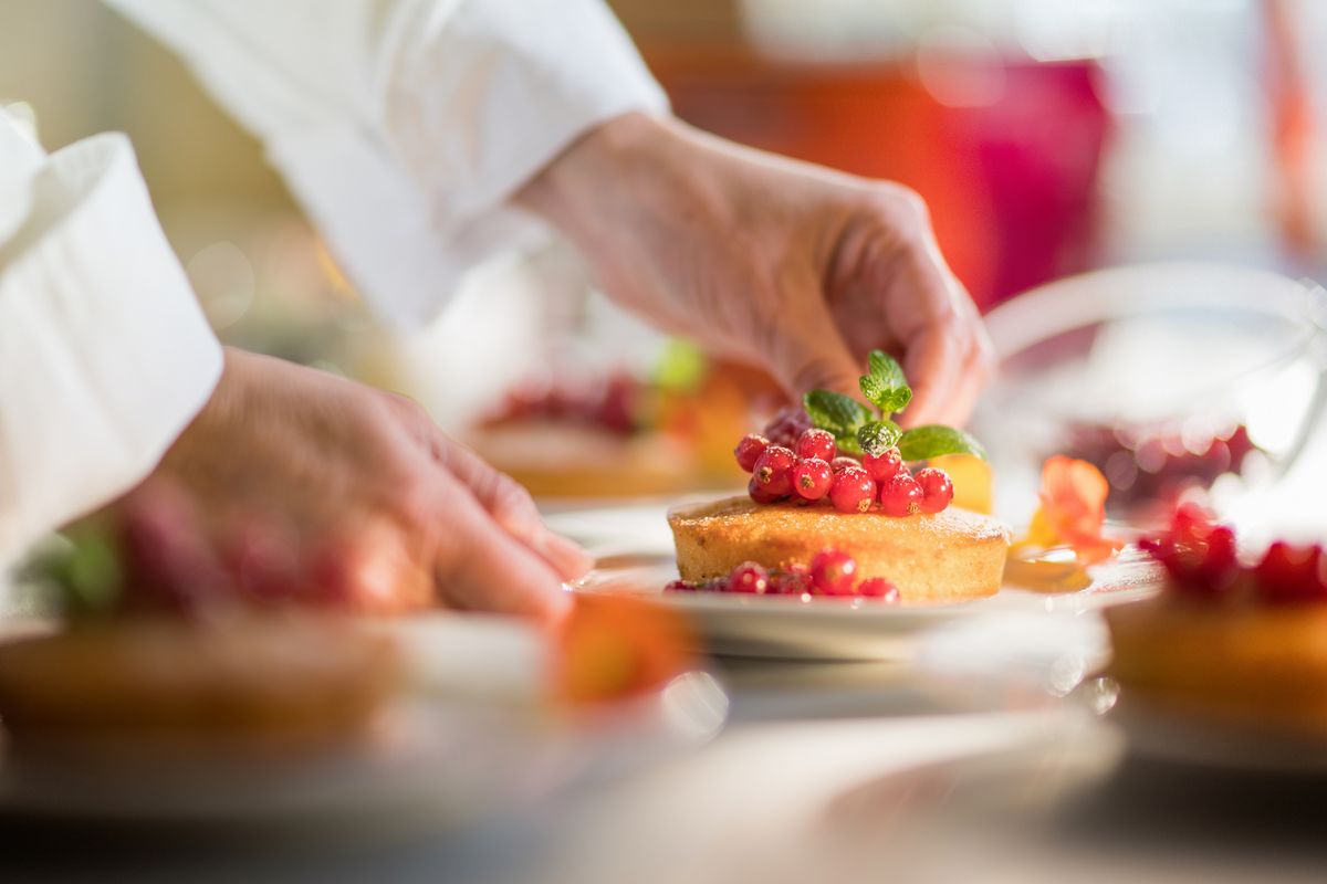 Primo piano delle mani di uno chef che prepara un delizioso dolce