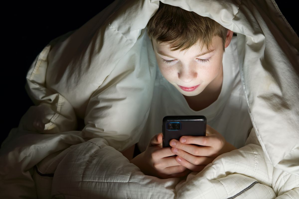 Bambino con smartphone a letto