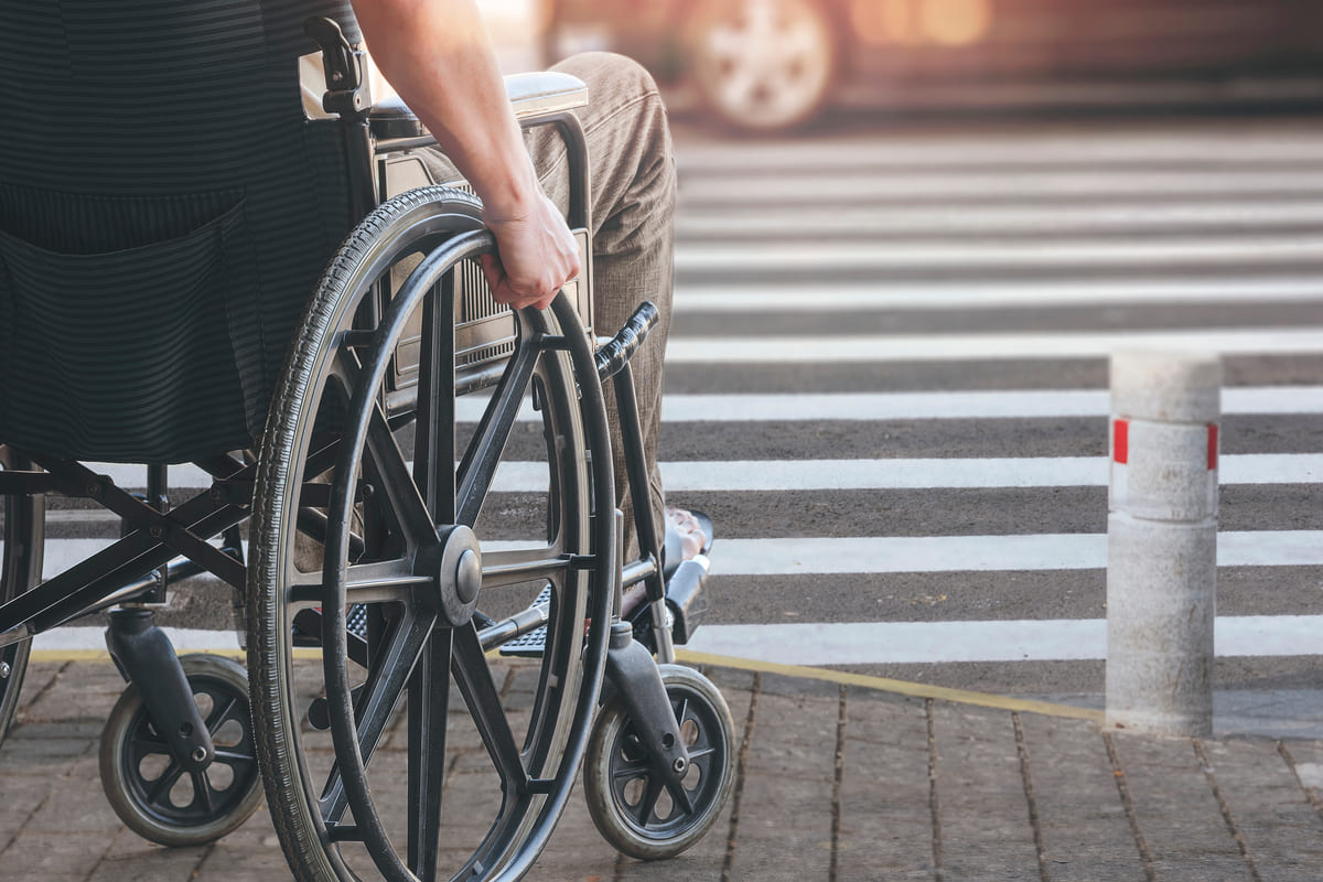 Un uomo disabile in sedia a rotelle attraversa sulle strisce pedonali