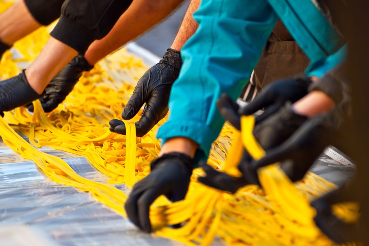 Operai di una fabbrica di pasta producono tagliatelle