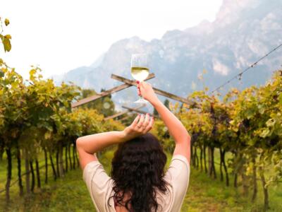 Una donna tiene un calice di vino in mezzo ad una vigna