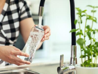 Una donna riempie una bottiglia dall'acqua del rubinetto