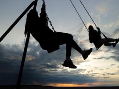 Due ragazze su un'altalena al tramonto